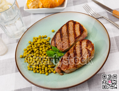 Fried beef cutlet with green peas on plate