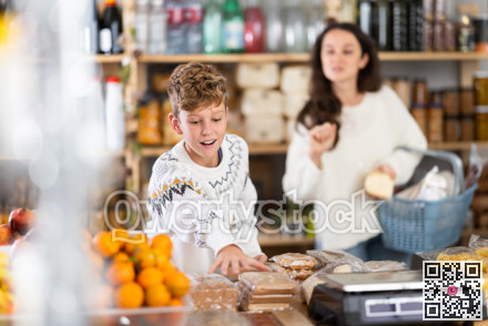 Teen boy selects sweets near window case in store, New Year Eve