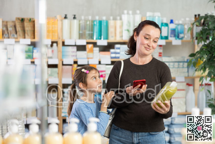 Woman with daughter scanning qr code of shampoo or shower gel