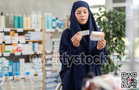 Young Muslim woman customer choosing pills in box in drugstore