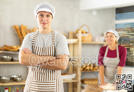 In working room of bakery, there is man with croissants in wicker basket in hands