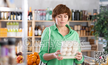 Adult woman choosing champignons in grocery store