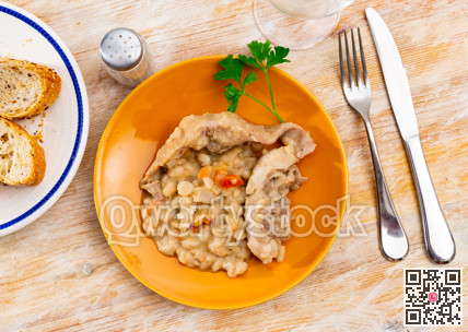 Fried rabbit on a plate with beans and parsley