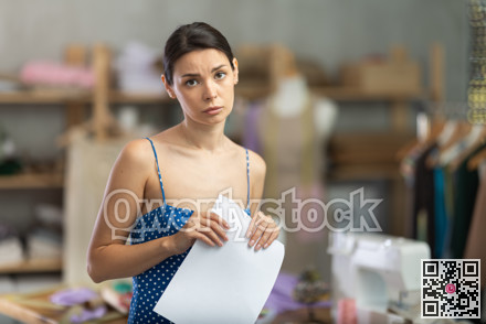 Upset woman seamstress with documents in workshop