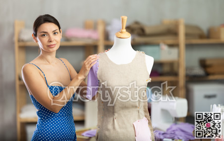 Woman seamstress adjusts clothes on mannequin