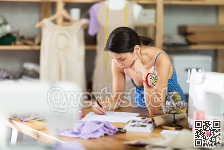 Young woman seamstress draws sketch on paper