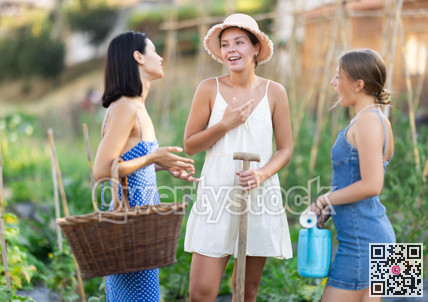 Three positive peasant girls are chatting in garden