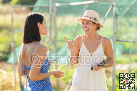 Two positive peasant girls are chatting in garden