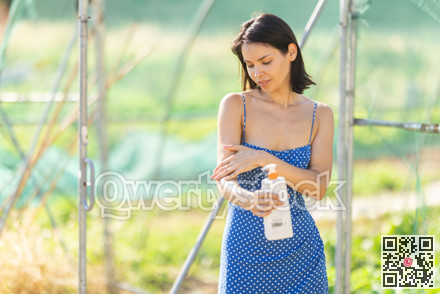 Adult woman applying sunscreen in garden greenhouse