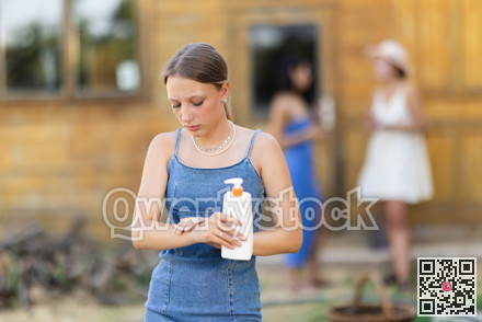 Young woman applying sunscreen outside country house
