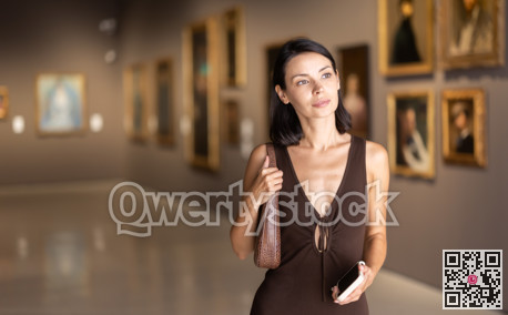 Woman visiting museum and looking at paintings in gold frames