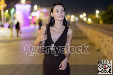 Woman walking along coastal promenade at night in Barcelona