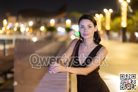 Girl standing with hands on parapet coastal area of Barceloneta at night