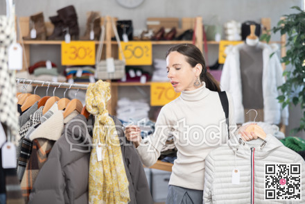 Middle-aged woman choosing down jacket in clothing store