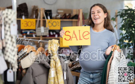 Pregnant woman holding sale sign in clothing store