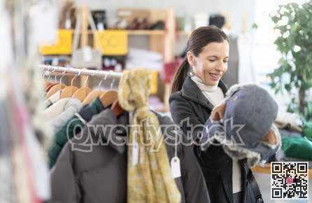 Glad middle-aged woman choosing fur hat in clothing store