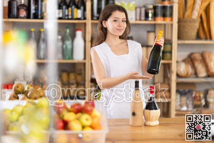 Young female shop assistant recommending bottle of wine