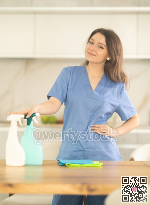 Young woman cleaner at table in kitchen