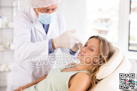 Male doctor gives injection and performs procedure of lip augmentation of female patient in clinic.
