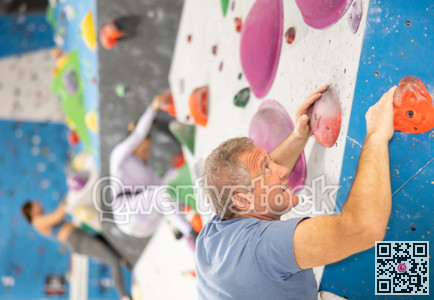 Older man climbing without ropes and harnesses on bouldering wall