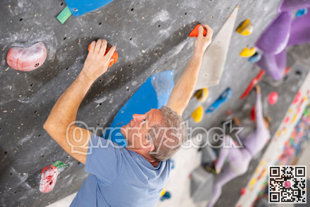 Adult man practicing rock climbing on climbing wall