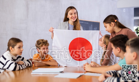 Female teacher shows scholchildren national flag of Japan