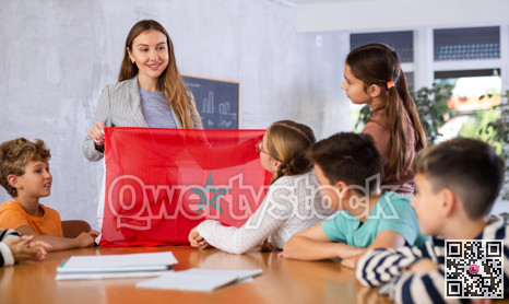 Female teacher shows scholchildren national flag of Morocco