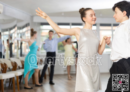 Enthusiastic teenagers performing waltz during group dance lesson
