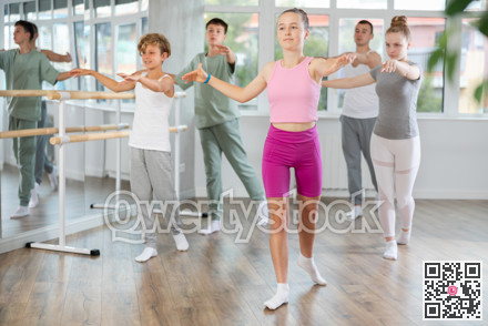 Young girl in group lesson with students rehearses, practices ballet dance, staging.