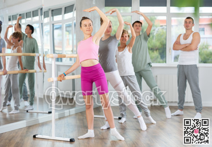 Teenage boys and girls practicing battement tendu position of ballet in dancehall