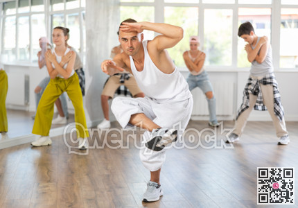Young man together with group of teenage students, learn to dance hip hop in choreographic hall