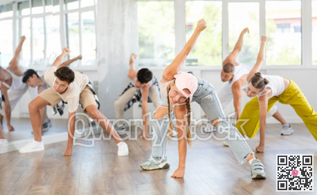 Team of teenagers rehearsing modern dances in dance hall
