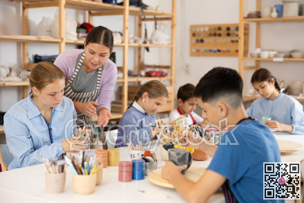 Children sit at the table and paint ceramics