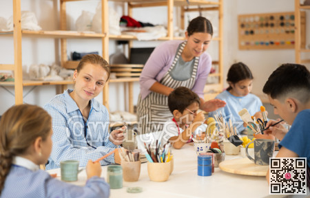Children painting ceramics with a teacher