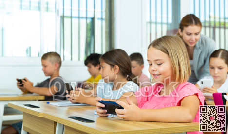 Pupils using mobile phones during lesson in school