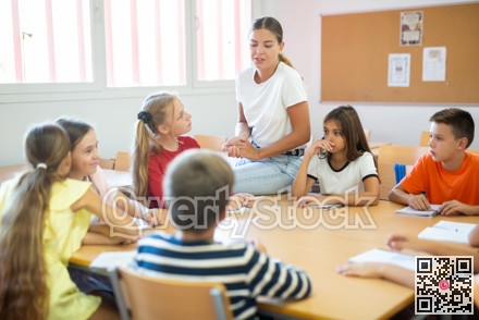 Friendly teacher explaining studying material to tweens sitting at common table
