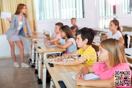 Group of school kids and teacher during lesson in classroom