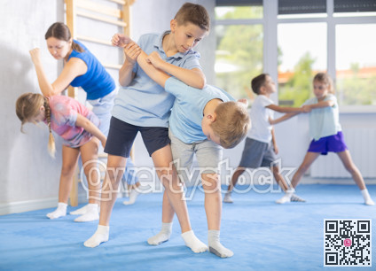 Children, boy and girl, working in pair mastering new self-defense moves at gym