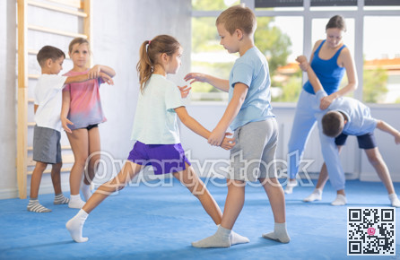 Boys and girls in gym perform basic elements of krav maga self-defense system.