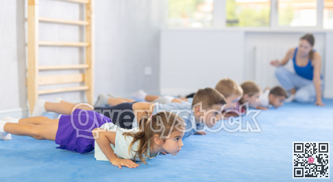 Child pupils performs exercises press-up before training martial arts