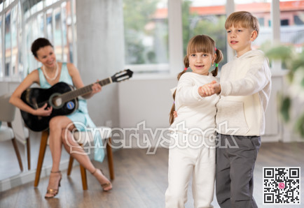 Boy and girl in pair train to dance tango during classes with accompaniment of guitar