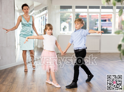 Kids learning cha-cha with female dance instructor in choreography studio