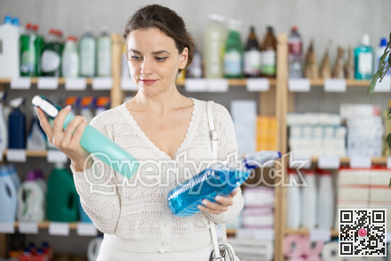 Young woman chooses cleaning spray in store