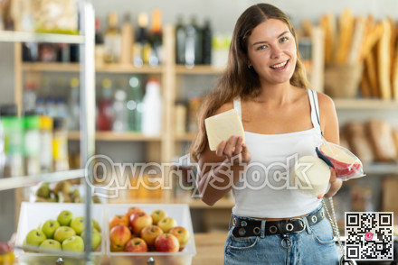 Young woman choosing cheese in grocery store