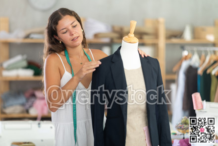 Female tailor fitting black blazer on mannequin