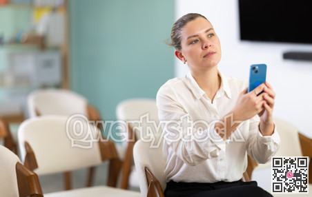 Young woman student scanning QR code with mobile phone
