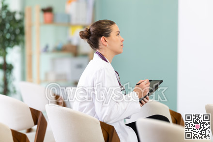 Female medical student listening to lecture in classroom with tablet