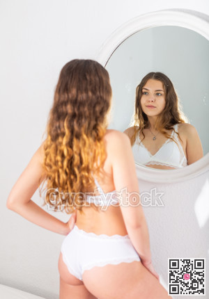 Portrait of young sexy woman in lingerie using mirror