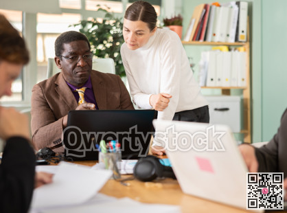 Female manager helping to man during working at laptop in office