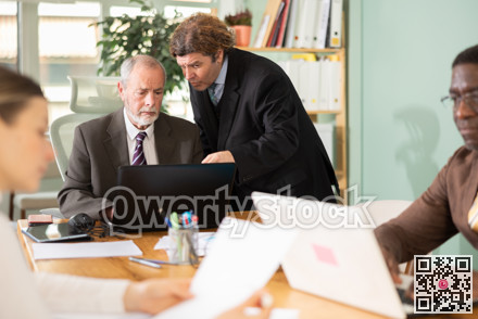 Middle aged man helping elderly employee with program on laptop